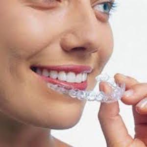 woman holding clear aligner to mouth